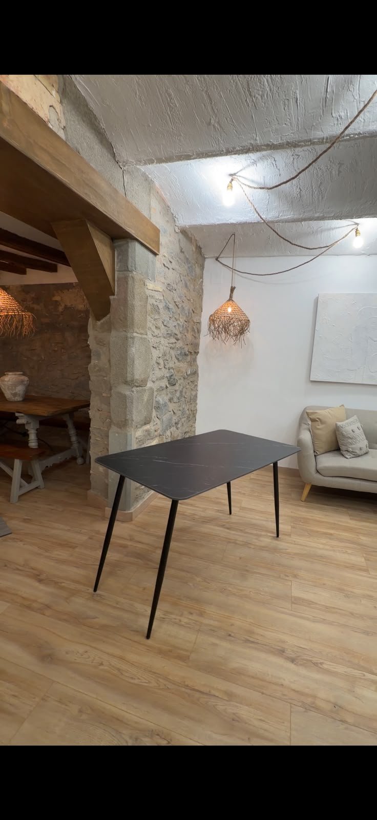 Mesa rectangular de sobre HPL efecto mármol negro en un espacio rústico de piedra